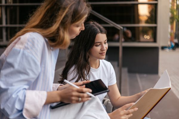 Etudiantes assises sur des marches consultant un dossier